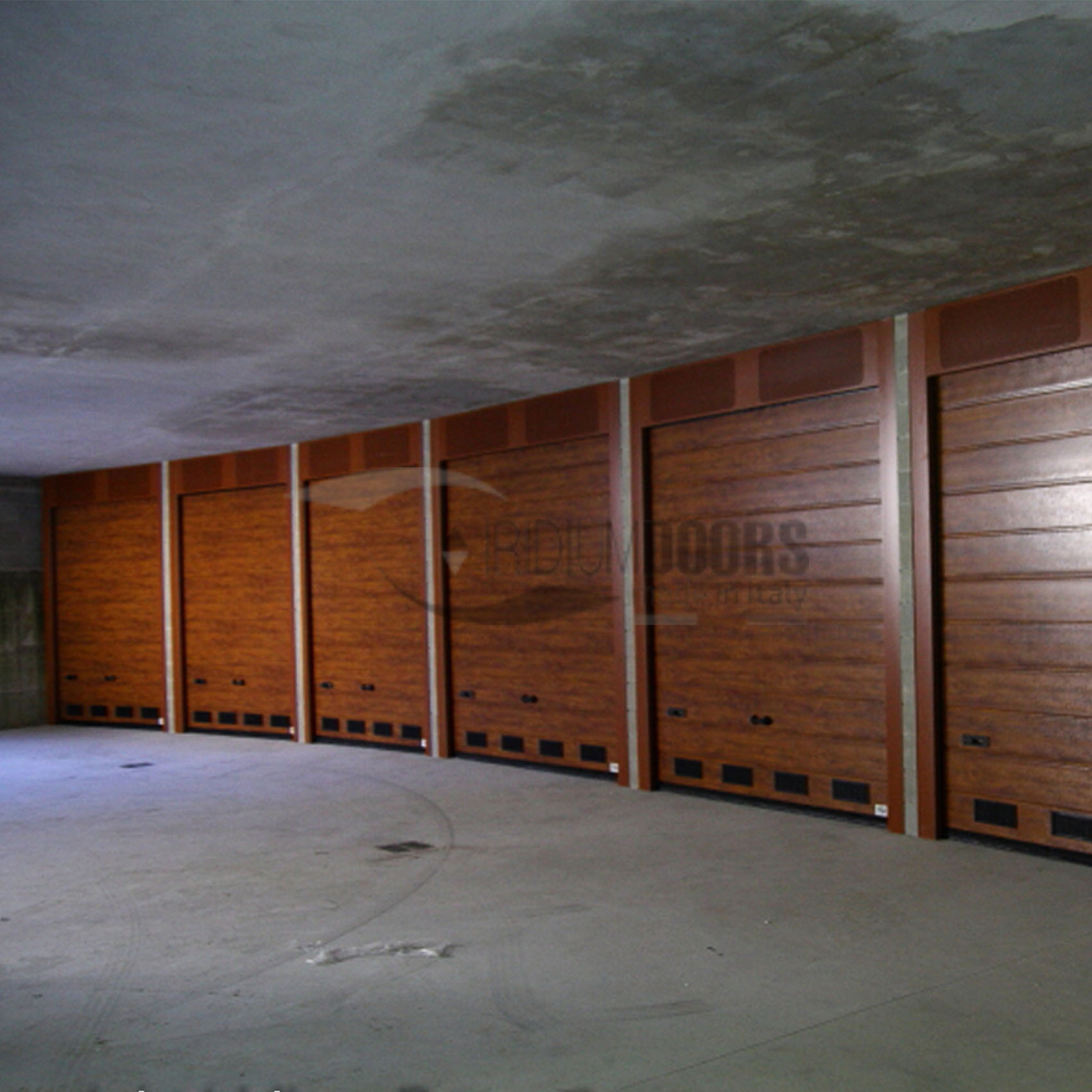 Portoni sezionali in tinta legno per condominio con velette a settori microforati verinicati e griglie di ventilazione in PVC nero Torino